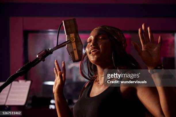 afrikaans-amerikaanse vrouwelijke singer die vocals op microfoon in de opnamecabine van de muziekstudio opneemt - popmuzikant stockfoto's en -beelden