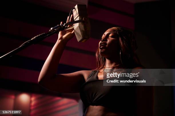 afroamerikanische künstlerin singt am mikrofon in musikstudio-aufnahmekabine - pink - singer stock-fotos und bilder