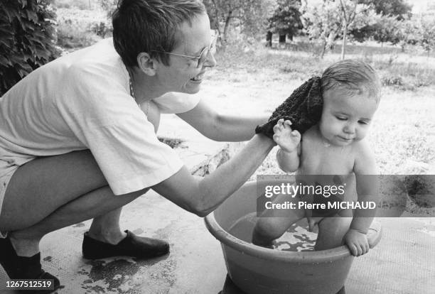 Femme donnant le bain à son petit fils dans le jardin, circa 1980, France.