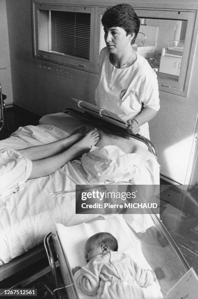 Sage-femme visitant une jeune maman dans une maternité, en 1988, France.