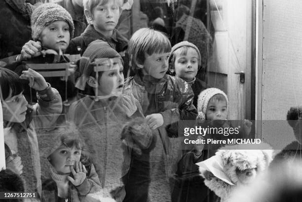 Enfants devant la vitrine de jouets d'un grand magasin avant les fêtes de Noël à Paris, en 1989, France.