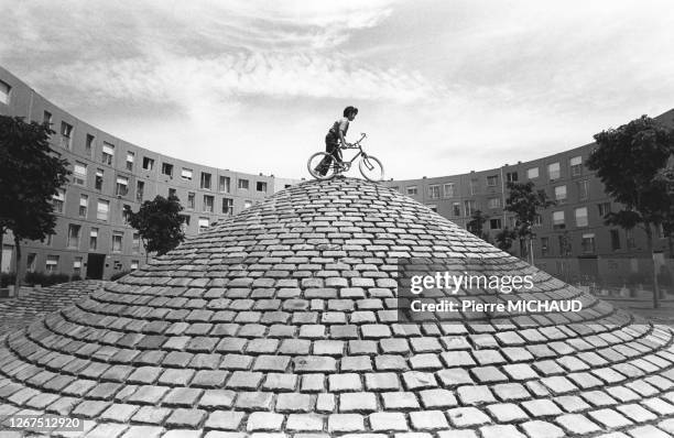 Enfant faisant du vélo sur les buttes en pavés d'un parc de la cité de La Grande Borne à Grigny, dans l'Essonne, circa 1980, France.