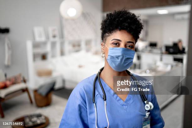 portrait of a young nurse/doctor on a house call with face mask - person of colour stock pictures, royalty-free photos & images