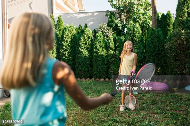 zwei schwestern spielen badminton in ihrem hinterhof - badminton stock-fotos und bilder