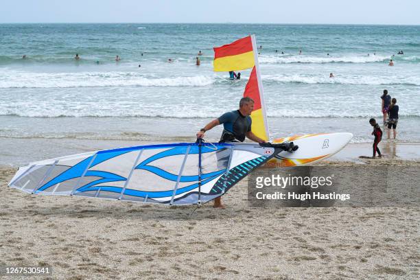 Windsurfer carries his board in strong winds as Storm Ellen continues to blow on the south west coast at Gyllyngvase Beach on August 21, 2020 in...