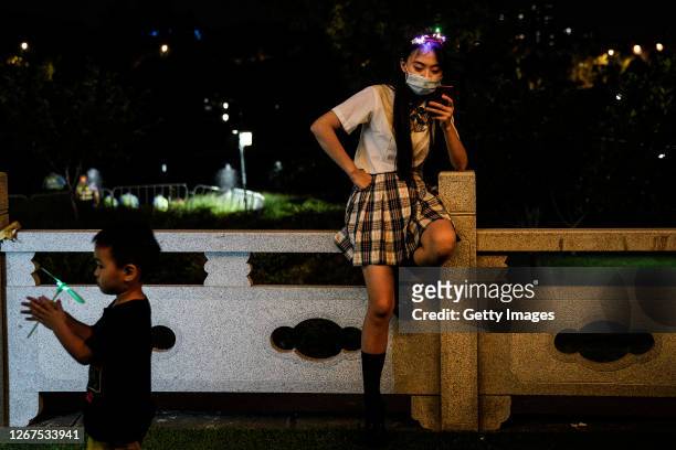 The lady uses an iPhone as a boy plays during Wuhan Beer Festival on August 21, 2020 in Wuhan, Hubei, China. As there have been no recorded cases of...