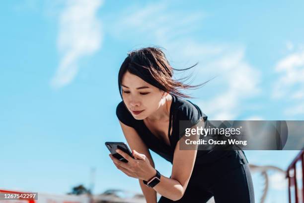 exhausted woman after fitness workout in the city - asian and indian ethnicities smartwatch phone stock pictures, royalty-free photos & images