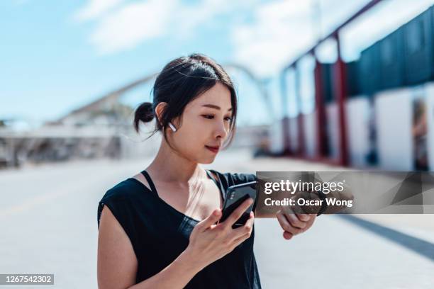 young woman using smartwatch and doing outdoor workout in the city - puntualidad fotografías e imágenes de stock