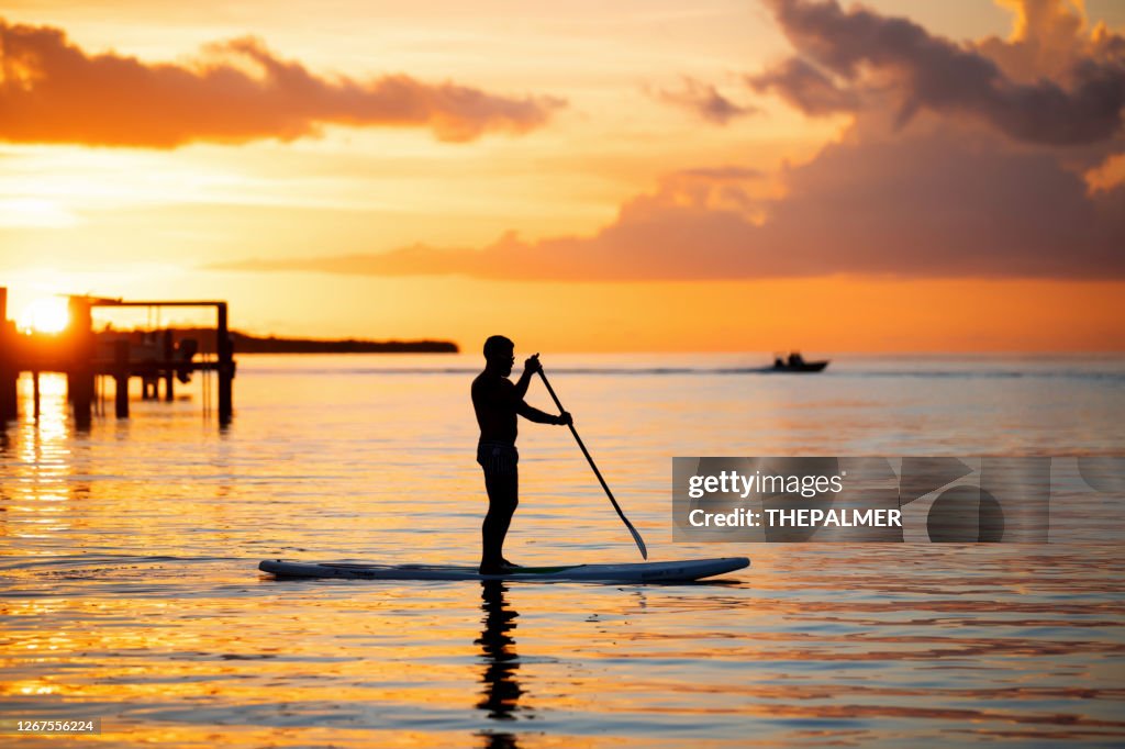 Silhoutte of man in his 30s paddle boarding in Florida