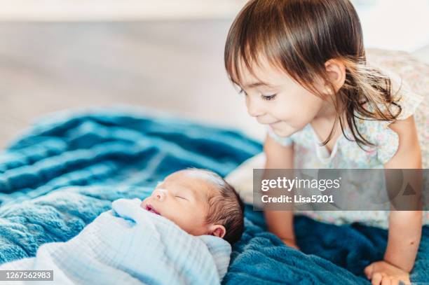 toddler gets to know her newborn baby sibling - siblings baby stock pictures, royalty-free photos & images