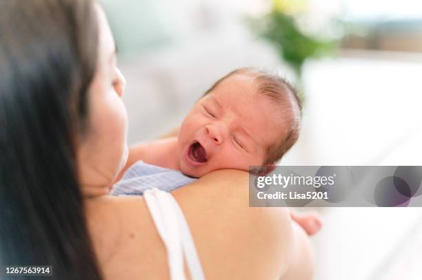 mother holds yawning newborn baby at home - latin american and hispanic ethnicity newborn stock pictures, royalty-free photos & images