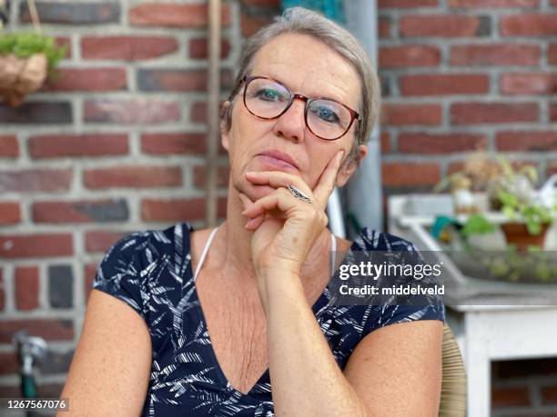 denkende vrouw met hand op kin - holland achtertuin stockfoto's en -beelden
