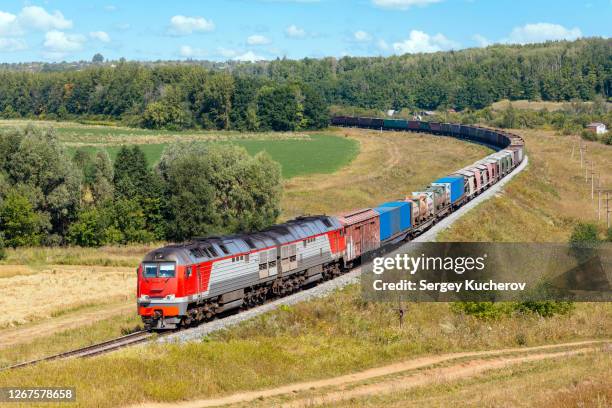 modern diesel engine hauling a heavy freight train in beautiful countryside - shipping containers green red stock-fotos und bilder