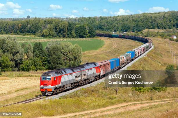 modern diesel engine hauling a heavy freight train in beautiful countryside - rail freight stock pictures, royalty-free photos & images