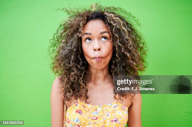 portrait of smiling woman making funny face with green background - comedian stock pictures, royalty-free photos & images