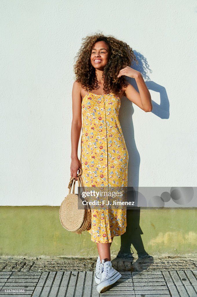 Woman with afro hair in front of white wall