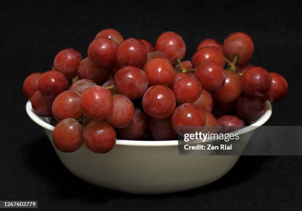 red grapes in white ceramic bowl against black background - freshness macro stock pictures, royalty-free photos & images