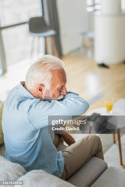 senior man coughing into elbow. - sneeze elbow stock pictures, royalty-free photos & images