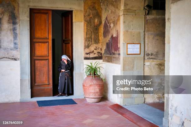 una monja sale de la puerta principal de un convento religioso en florencia - tunic fotografías e imágenes de stock