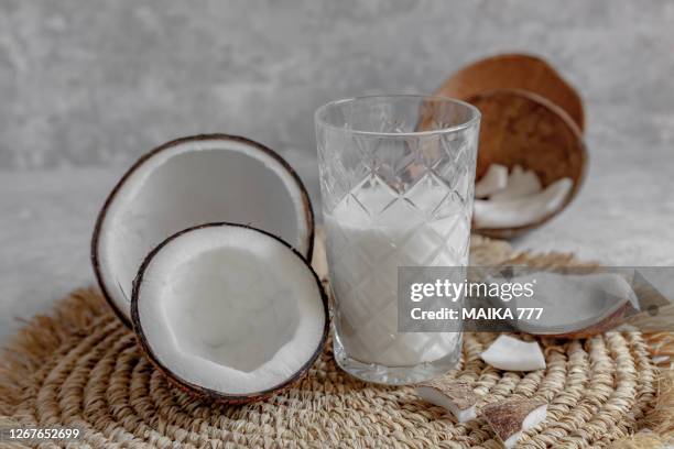 opened coconuts, glass of homemade coconut milk and coconut chunks - kokoswater stockfoto's en -beelden