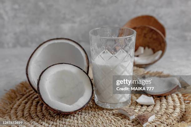 opened coconuts, glass of homemade coconut milk and coconut chunks - kokosmelk stockfoto's en -beelden