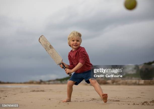 een jonge jongen speelt veenmol op het strand. - beach cricket stockfoto's en -beelden