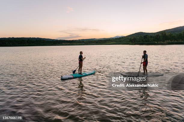 vater und tochter stehen auf einem see - paddle stock-fotos und bilder