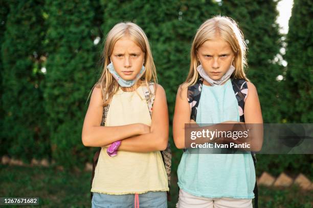 portrait of twin sisters with face masks going to school - furious child stock pictures, royalty-free photos & images