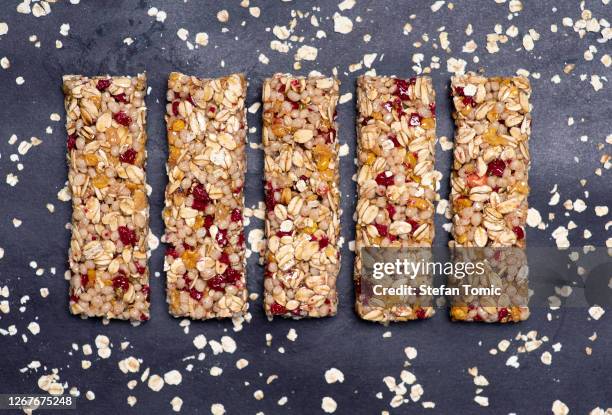 protein-energieriegel mit vollkorngetreide und himbeerfrüchten auf dunklem hintergrund isoliert - muesli bar stock-fotos und bilder