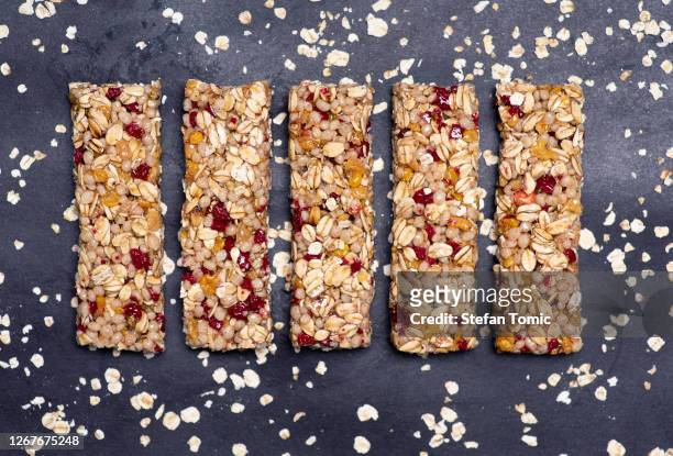 de staaf van de eiwitenergie met volkorengraangewassen en het fruit van de frambozen op donkere geïsoleerde achtergrond - cereal bar stockfoto's en -beelden