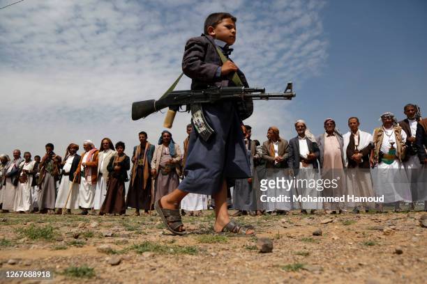 Child carrying a rifle walks during a rally held by loyalists of the Houthi group against the announcement of the diplomatic normalization between...