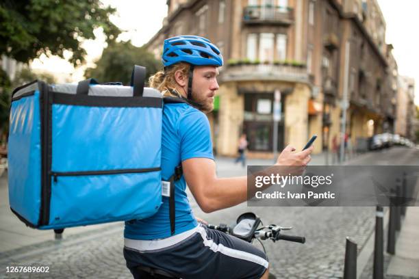 side view of a young caucasian delivery man delivering food - food delivery stock pictures, royalty-free photos & images