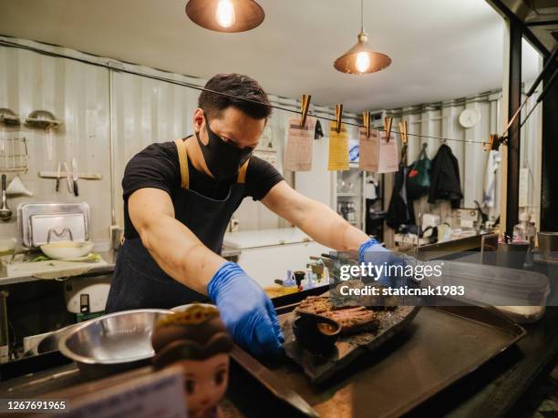 geschäftsinhaber eröffnet ein restaurant, während er eine gesichtsmaske trägt - food safety stock-fotos und bilder