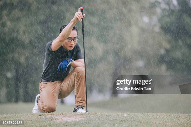 asiatische chinesische männliche golfer schlange stehen messen golf spielen im regen in melaka allein nass - golfhandschuh stock-fotos und bilder