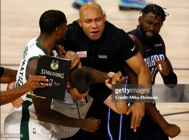 Referee Kevin Scott and Milwaukee Bucks assistant coach Darvin Ham break up a fight between Marvin Williams of the Milwaukee Bucks grabs and James...