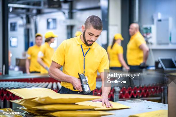 distribution warehouse worker scanning packages with a bar code reader. - sorting office stock pictures, royalty-free photos & images