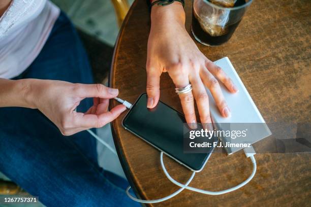 close-up of woman's hands plugging a mobile phone into a power bank - power bank imagens e fotografias de stock