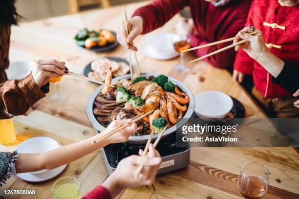 close up of three generations of joyful asian family celebrating chinese new year and enjoying scrumptious traditional chinese poon choi on reunion dinner - chinese new year food stock pictures, royalty-free photos & images