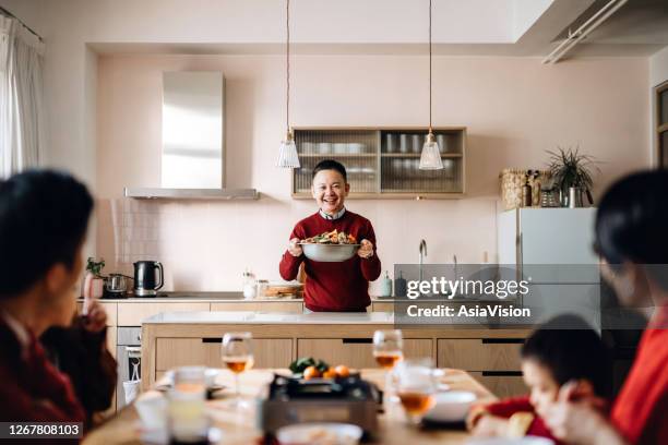 three generations of joyful asian family celebrating chinese new year and grandfather serving scrumptious traditional chinese poon choi on reunion dinner - serving dish stock pictures, royalty-free photos & images