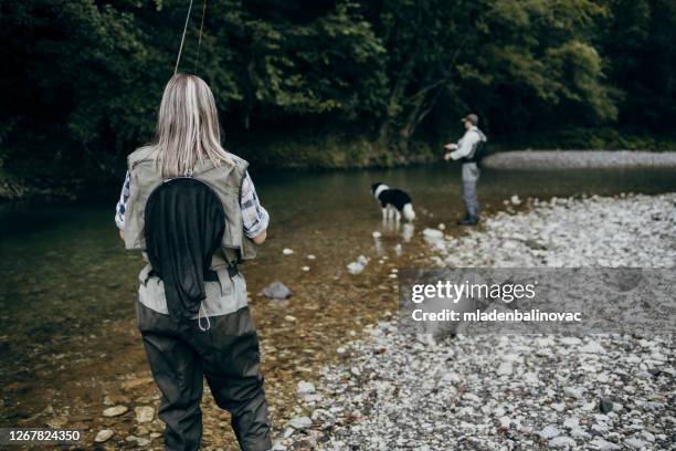 young adult couple is fishing together on fast mountain river. active people and sport fly fishing concept. - fly casting imagens e fotografias de stock