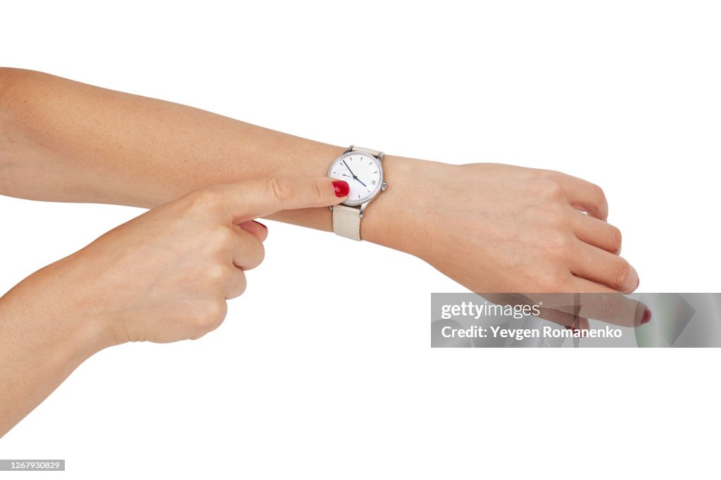 Woman points with her finger on a clock face of a wristwatch on her wrist