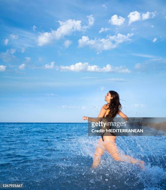 bikini girl tourist running in the beach splashing water happy - swimsuit models girls stock pictures, royalty-free photos & images