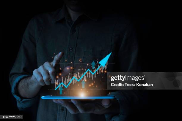 businessman with a tablet is showing a growing virtual hologram stock and finance and investment concept - trader ストックフォトと画像