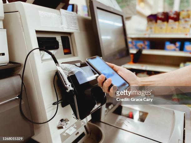 man makes contactless payment at self-checkout kiosk - counter stand stock-fotos und bilder