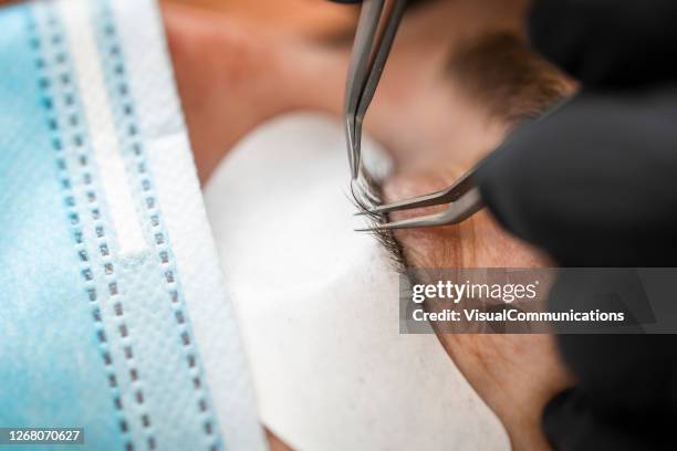 eyelash technician and customer wearing protective masks and gloves during the treatment. - eyebrow tweezers imagens e fotografias de stock