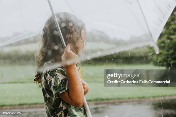 young girl holding an umbrella in the rain - sad kid in kindergarten stock pictures, royalty-free photos & images