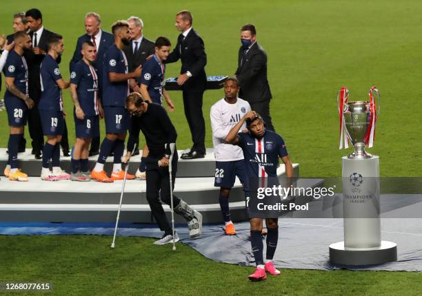 Kylian Mbappe of Paris Saint-Germain removes his runners up medal as he walks past the UEFA Champions League Trophy following his team's defeat in...