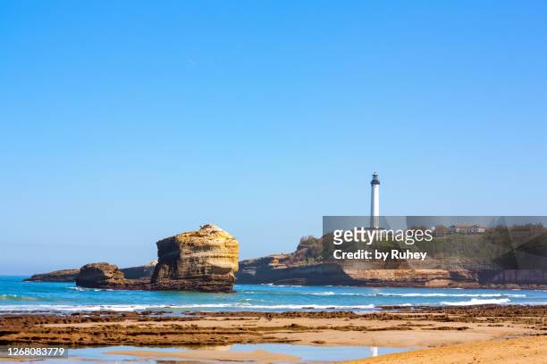 miramar beach in biarritz with the lighthouse in the background and the reflection of the sea with its characteristic rock in the foreground - biarritz stockfoto's en -beelden