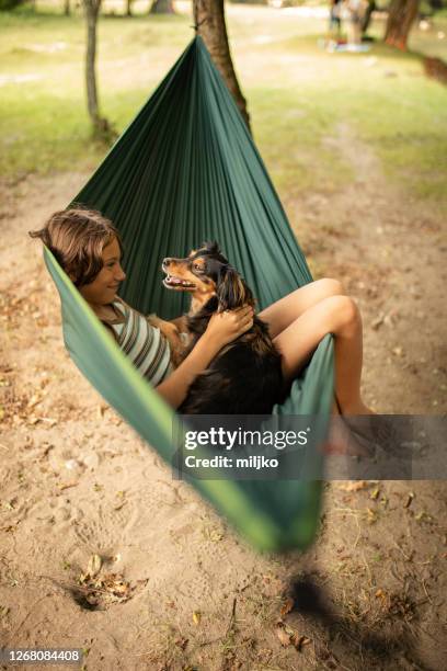 boy relaxing in hammock with her dog - hammock camping stock pictures, royalty-free photos & images
