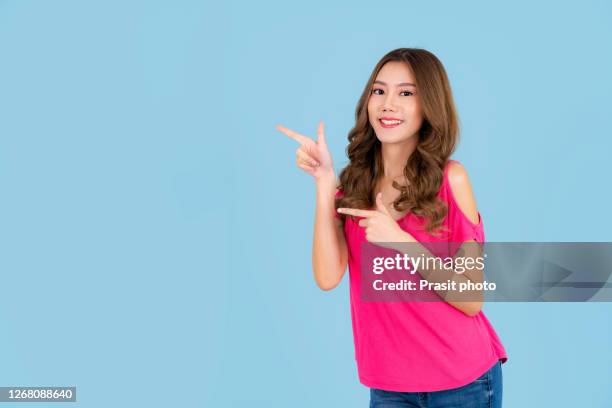 banner of young happy asian woman feeling happiness and gesture hand open on cyan background. cute asia girl smiling wearing pink casual dress and present on copy space. - hand pointing ストックフォトと画像